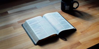 opened book beside black ceramic mug