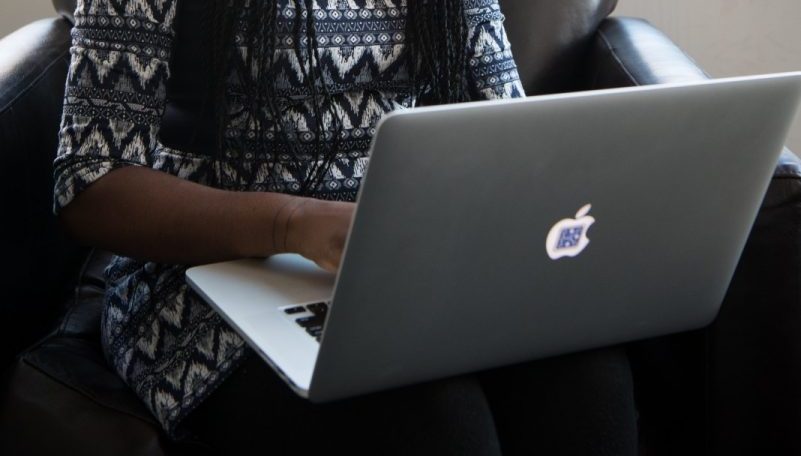 woman using MacBook while sitting on a sofa chair